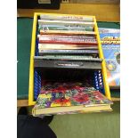A plastic crate containing a small assortment of books to include toy trains, racing, etc