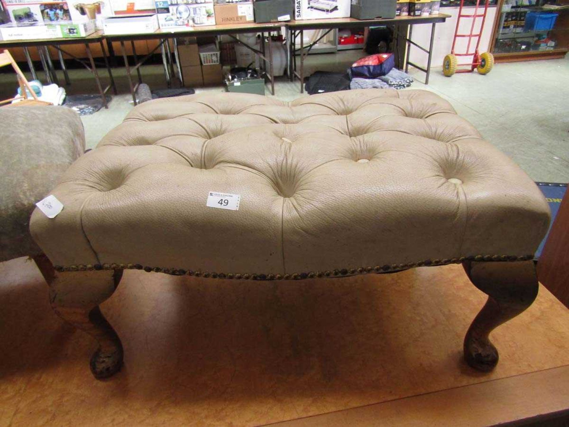 A cream leather upholstered footstool on cabriole supports