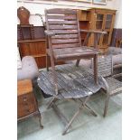 A weathered wooden folding circular topped garden table together with a distressed garden chair