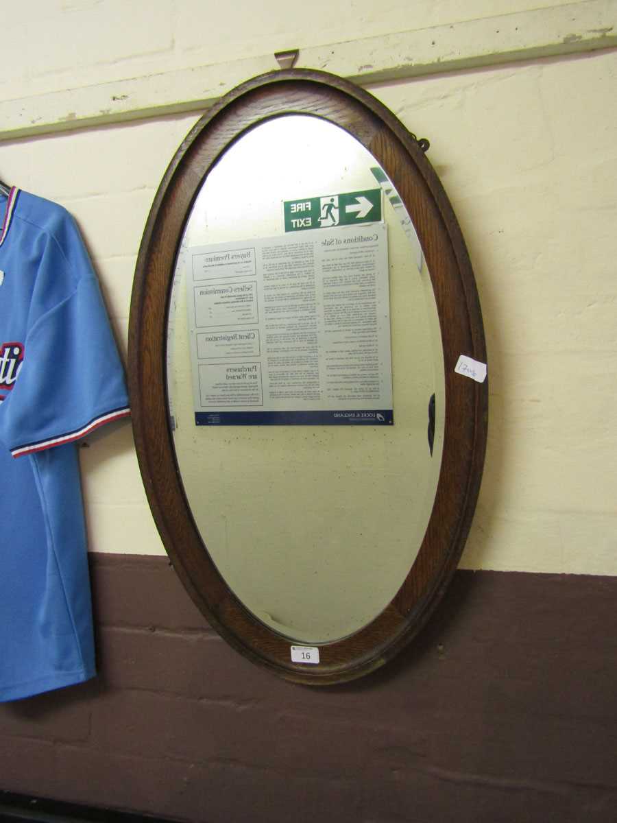 An early 20th century oval oak framed bevel glass wall mirror