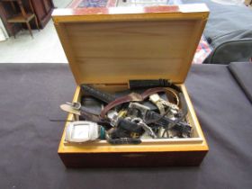 A wooden box containing a quantity of used wristwatches