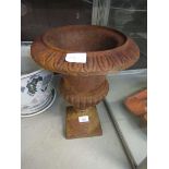 An early 20th century rusted cast metal urn