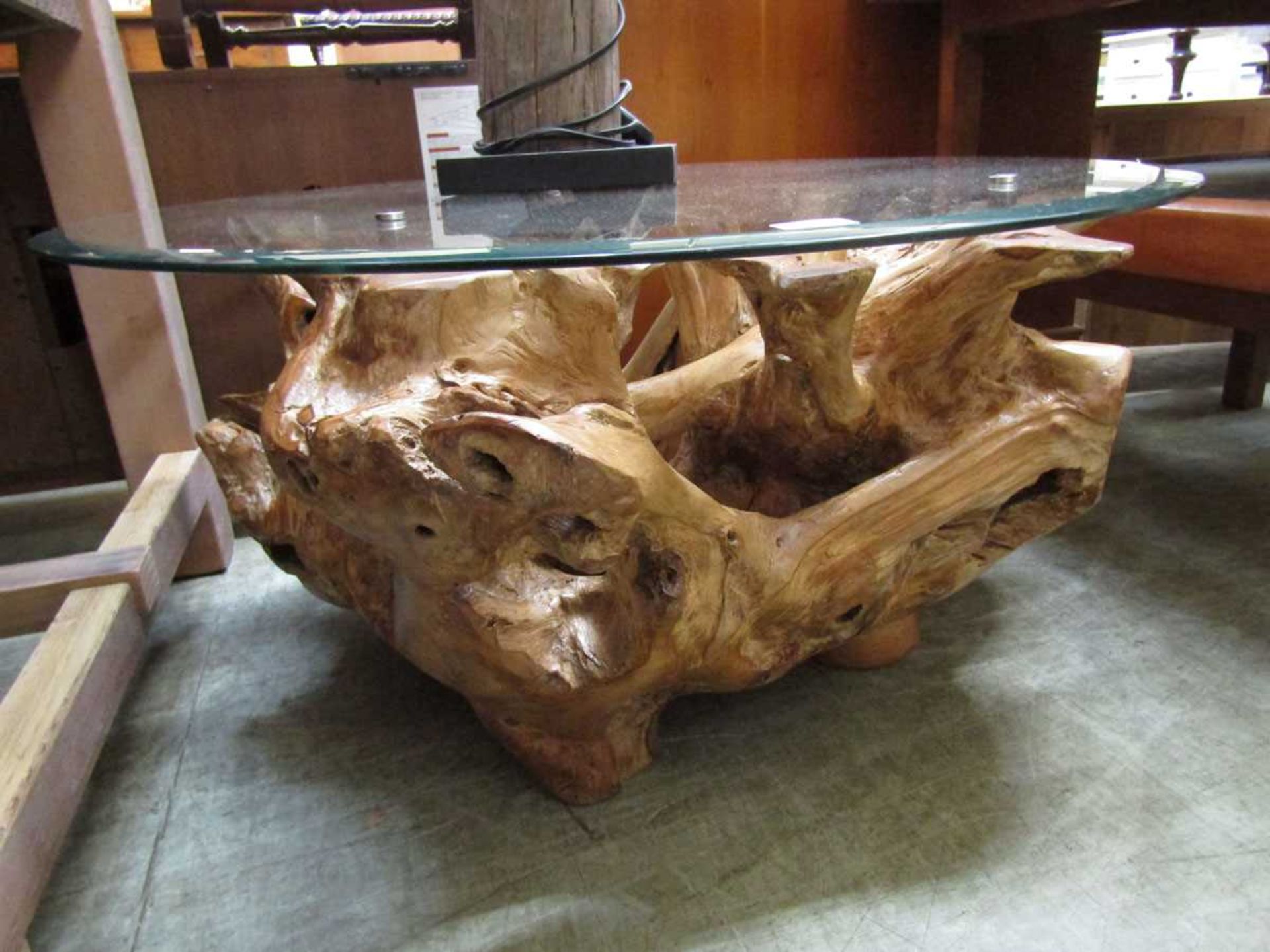 A wooden root design occasional table with a circular bevel glass top