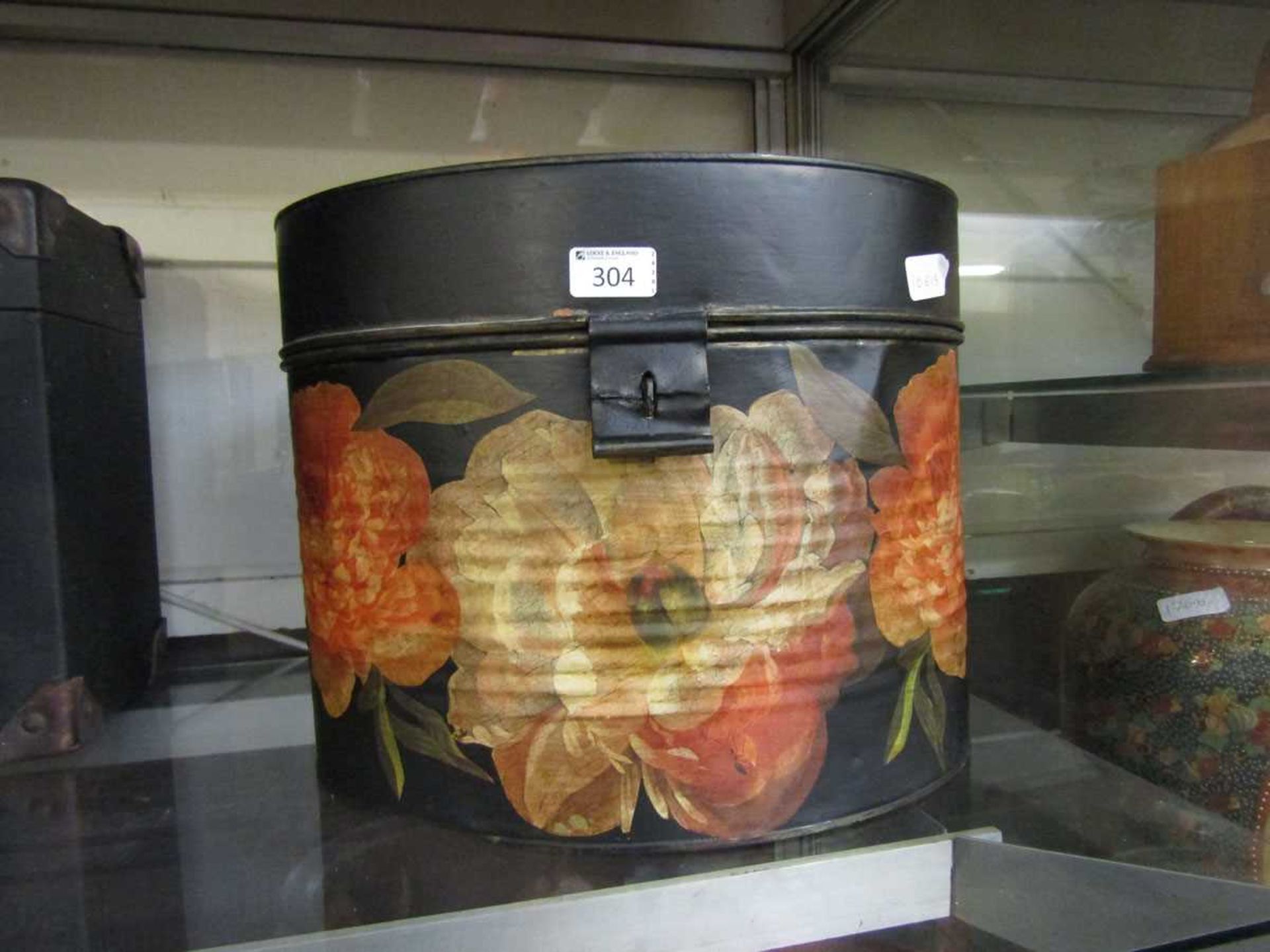 A black and floral painted tin hat box