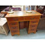 A reproduction yew twin pedestal desk with a tan tooled leather inset to top