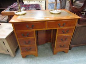 A reproduction yew twin pedestal desk with a tan tooled leather inset to top