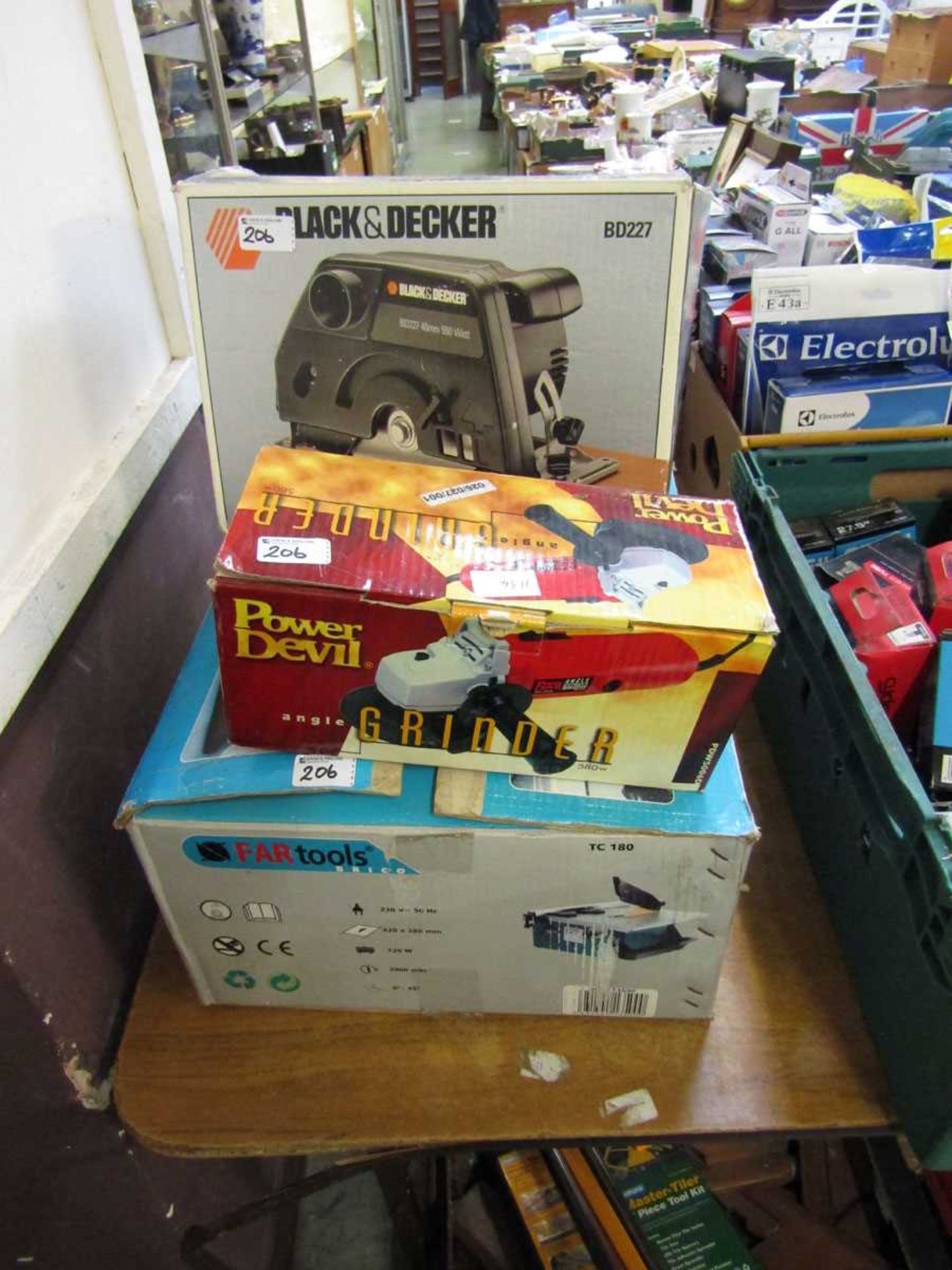 A boxed angle grinder along with a boxed Black and Decker rotary saw and a boxed table saw