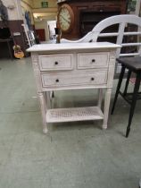 A cream painted French style cabinet having two short over one long drawer with bergere under tier