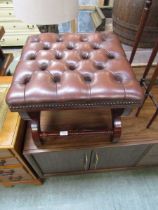 A reproduction mahogany cross membered stool having button leatherette seat