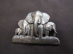 A white metal brooch of elephants with inscription to back 'The David Shepherd Conservation