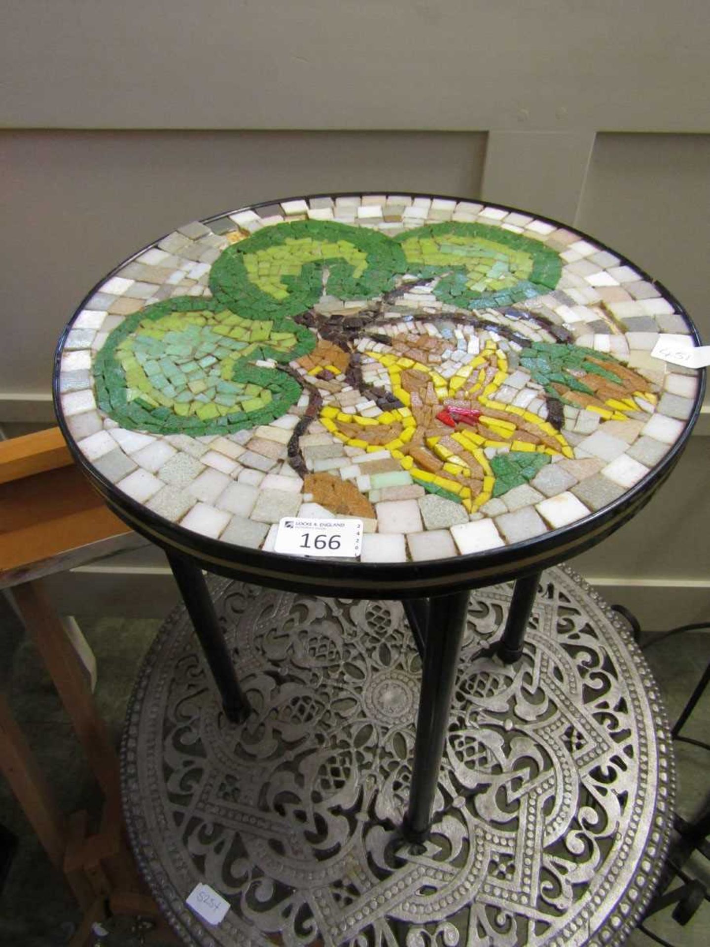 A mosaic style circular topped table on metal base