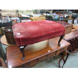 A mahogany cabriole legged stool with a distressed red velvet overstuffed seat