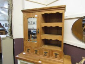 A waxed pine wall mounted cabinet having mirrored door beside open storage with four small drawers