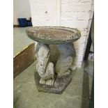 A weathered stoneware garden birdbath having a pelican design