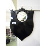 An early 20th century black painted shield back hall mirror with three hooks