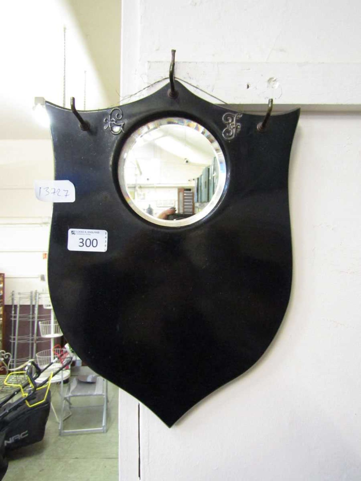 An early 20th century black painted shield back hall mirror with three hooks