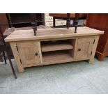 A modern oak TV cabinet having open storage flanked by cupboard doors