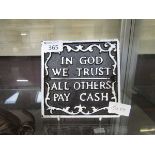 A reproduction metal sign 'In God We Trust, All Others Pay Cash'