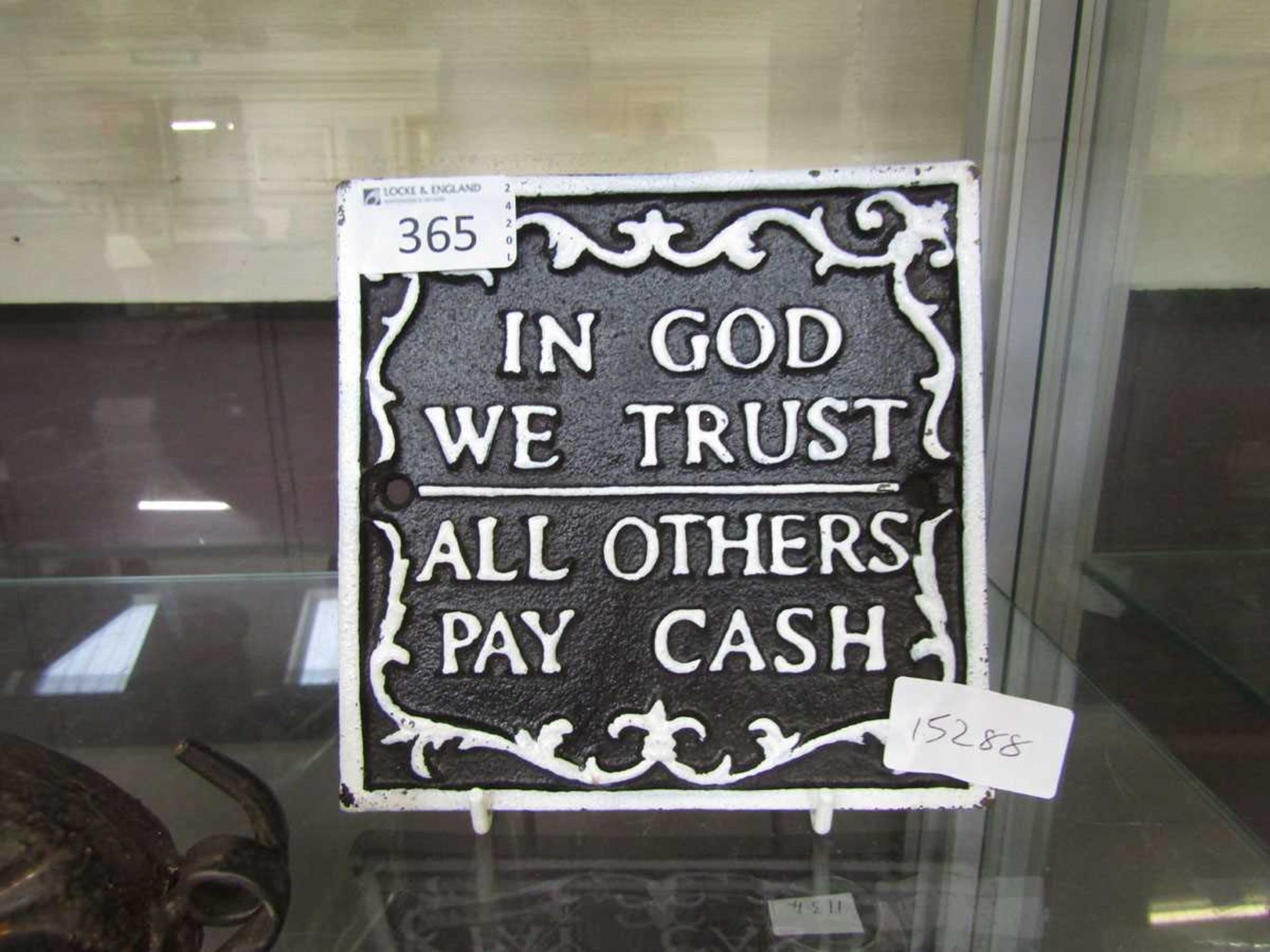 A reproduction metal sign 'In God We Trust, All Others Pay Cash'