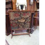 A late Victorian oak framed fire screen having a needlework to front