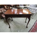 An early 20th century walnut fold over games table with ball and claw feet