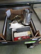 A box containing an assortment of metalware to include flatware, pewter tankard, collector's