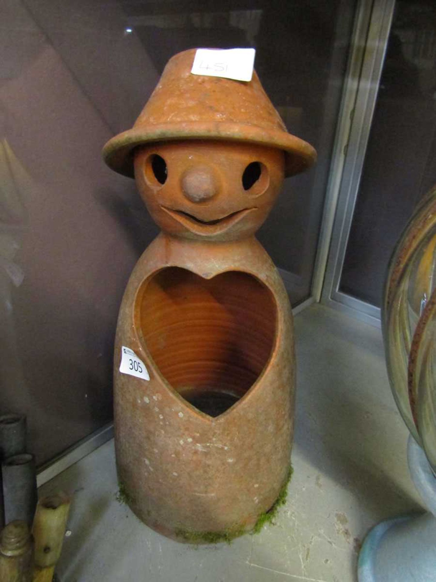 A terracotta garden ornament in the form of a man with heart shaped hole in chest