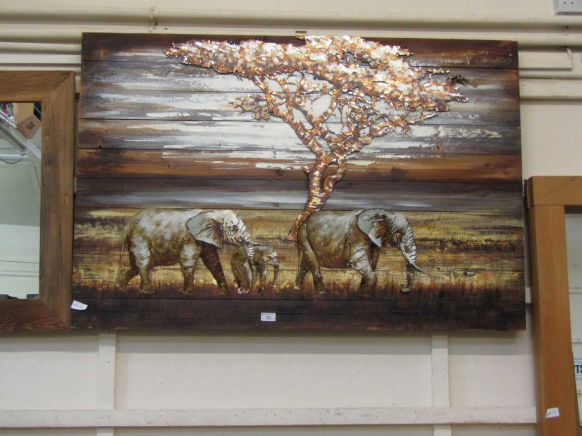 A modern wooden wall plaque having a cut out metal elephant and tree design