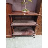 A mahogany three tier buffet table on wheels