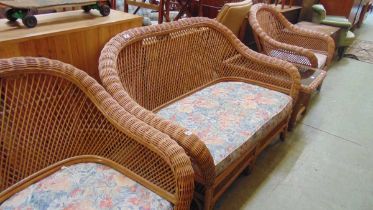 A cane and wicker conservatory suite comprising of a settee, two matching chairs, and a coffee table