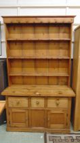 An early 20th century waxed pine dresser having plate rack to top, the base having three small