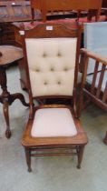 An early 20th century nursing chair with carved back with cream overstuffed back and seat cushion