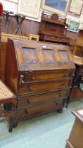 An early 20th century oak fall front bureau having linen fold design to fall with four graduated