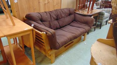 A modern beech framed settee with drop ends and brown upholstered cushions approx 75cm