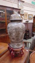 A reproduction eastern style ceramic urn with foo dog design lid on carved and pierced wooden base