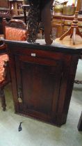 A George III oak wall mounted corner cupboard, with fielded panel door with medullary rays enclosing