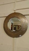 A modern hammered metal circular bevel glass wall mirror