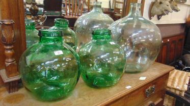 A pair of green glass carboys together with a large pale green glass carboy
