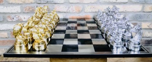 CHESS SET, chequered board complete with silvered and gilt finish animal form pieces, 60cm x 60cm.