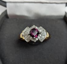 A 9CT GOLD RHODOLITE GARNET SET DRESS RING, the central cushion cut stone of 0.50 carat,