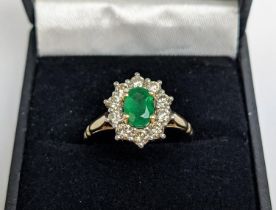 A 9CT GOLD EMERALD AND DIAMOND RING, the central emerald of 0.85 carats surrounded by round