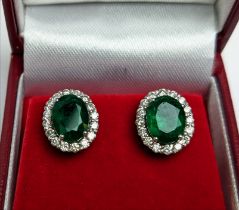A PAIR OF 18CT WHITE GOLD EMERALD AND DIAMOND STUD EARRINGS, the central emerald stones of 2.76