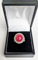 A RUBY AND DIAMOND DRESS RING, white metal shank, the central ruby cabochon of approx 10 carats,