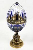 FABERGE EGG, number four,, clear cut glass with blue inclusions on mythical entwined fish column,