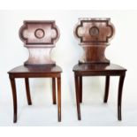 HALL CHAIRS, a pair, Regency style mahogany with cartouche inset backs and sabre front supports,