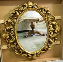 OVAL WALL MIRROR, 128cm x 135cm H, 20th century with a scrolling giltwood frame and bevelled plate.