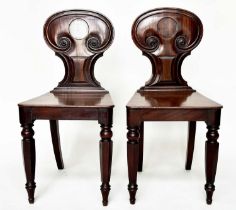 HALL CHAIRS, a pair, Regency period mahogany with shaped, scroll-carved backs and facetted front