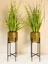 POTTED FAUX PLANTS, 140cm high, 50cm diameter, a pair, in gilt planters on stands, black painted
