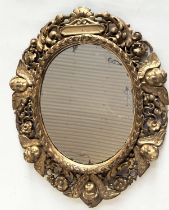 WALL MIRROR, early 19th century Italian carved giltwood oval with carved cherubs and foliate detail,