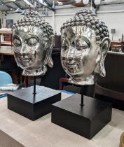 BUDDHA BUSTS, a pair, silvered resin, on stands, 49cm H. (2)